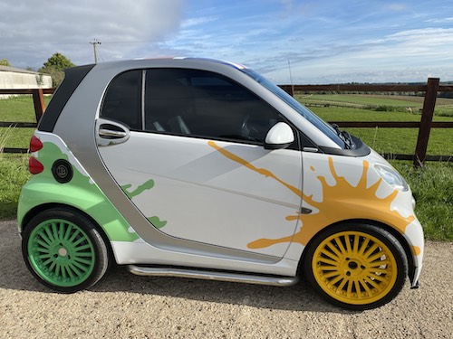 White Smart Car with custom paint job with green and yellow splats