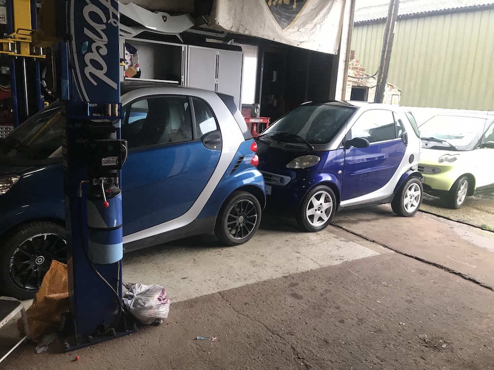Smart Cars parked in a row, one behind the other, in a garage.